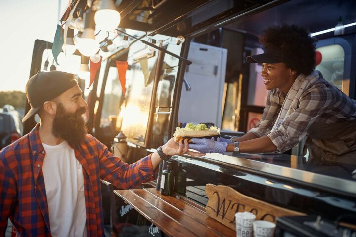 A smiling employee serves a customer from a food truck