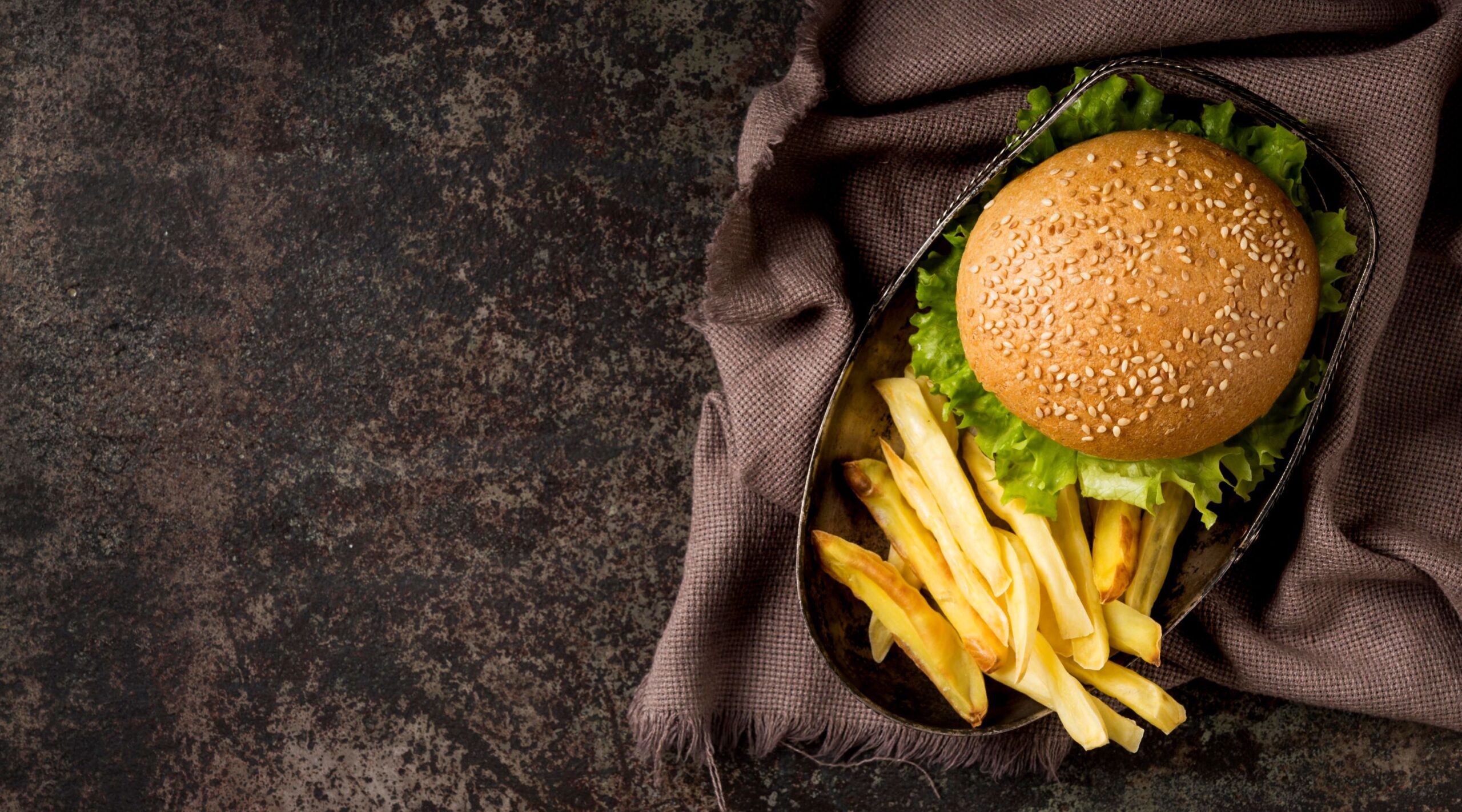 A top view of a burger and fries on a plate with a kitchen towel underneath