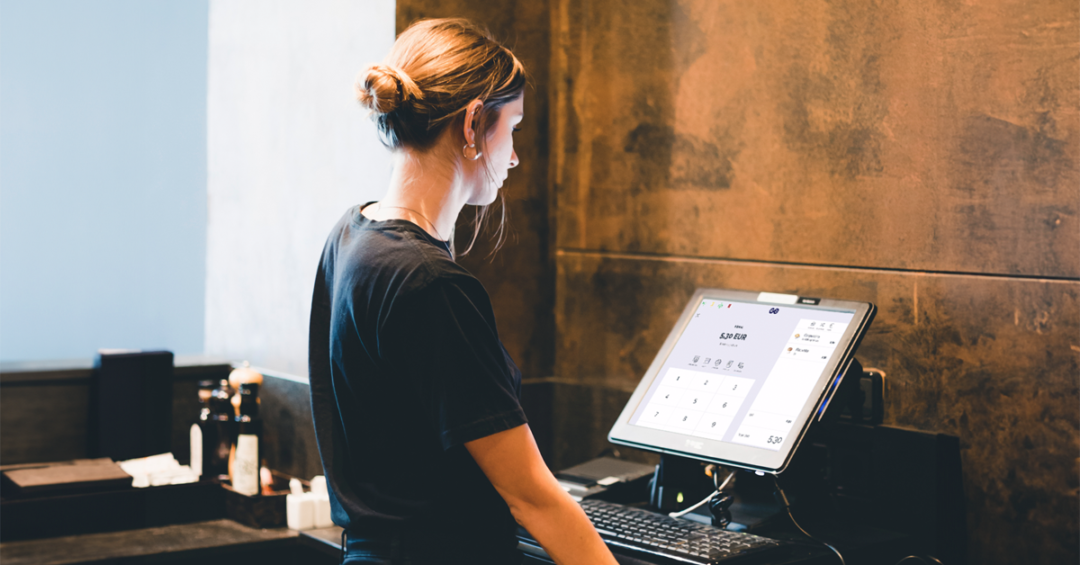 woman in a black t-shirt looking at a screen with a pos system in a store